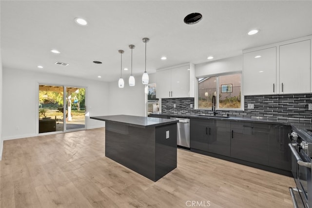 kitchen featuring visible vents, dark countertops, modern cabinets, appliances with stainless steel finishes, and a sink