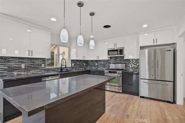 kitchen with decorative light fixtures, sink, white cabinets, a center island, and stainless steel appliances