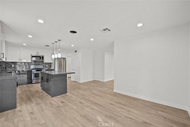 kitchen featuring pendant lighting, tasteful backsplash, white cabinets, a center island, and stainless steel appliances