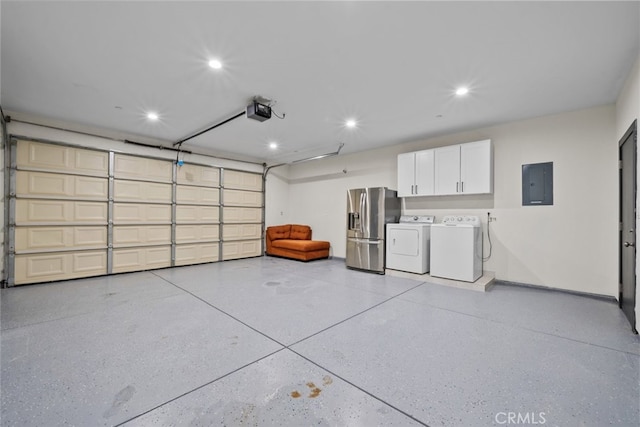 garage with a garage door opener, stainless steel fridge, electric panel, and washer and dryer