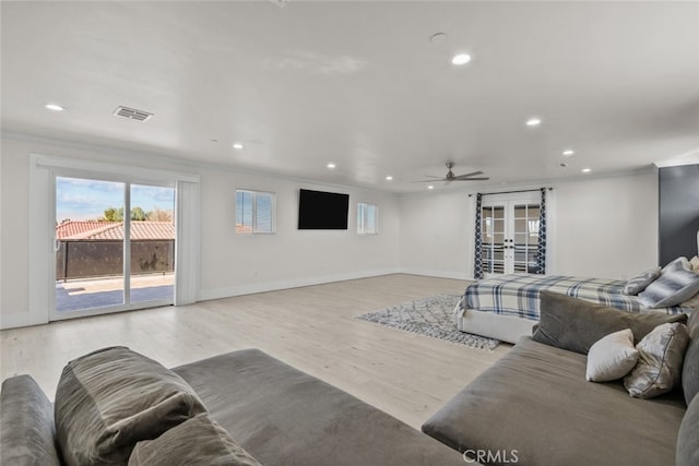 living room featuring ornamental molding, french doors, ceiling fan, and light wood-type flooring