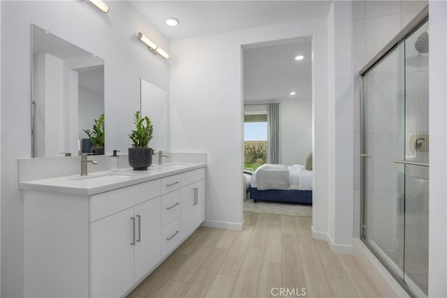 bathroom with hardwood / wood-style flooring, vanity, and a shower with door