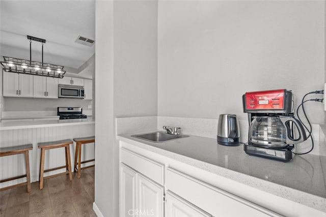 kitchen featuring sink, white cabinetry, hanging light fixtures, stainless steel appliances, and dark hardwood / wood-style floors