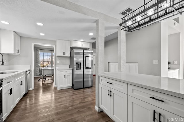 kitchen with sink, dark hardwood / wood-style flooring, stainless steel appliances, light stone countertops, and white cabinets