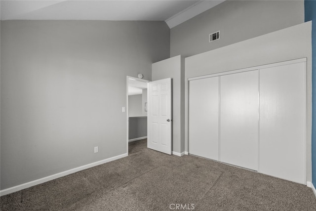 unfurnished bedroom with high vaulted ceiling, a closet, and dark colored carpet