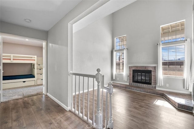 hall with plenty of natural light, dark hardwood / wood-style floors, and a towering ceiling