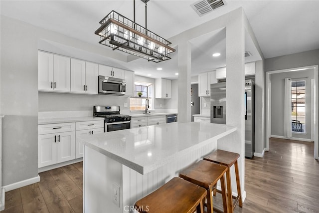 kitchen with hanging light fixtures, appliances with stainless steel finishes, and white cabinets