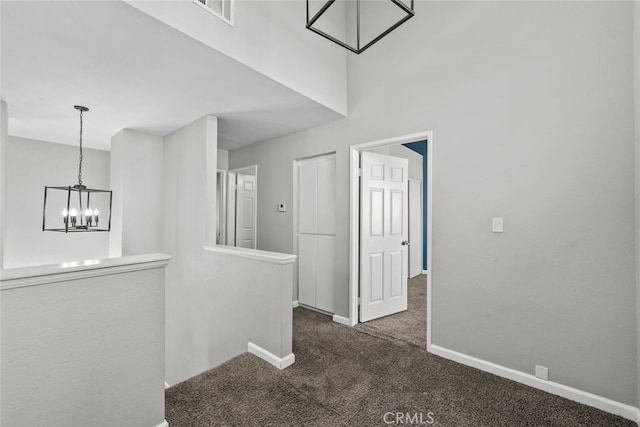 corridor with a chandelier and dark carpet