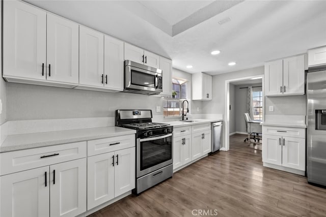 kitchen with stainless steel appliances, sink, white cabinets, and dark hardwood / wood-style floors