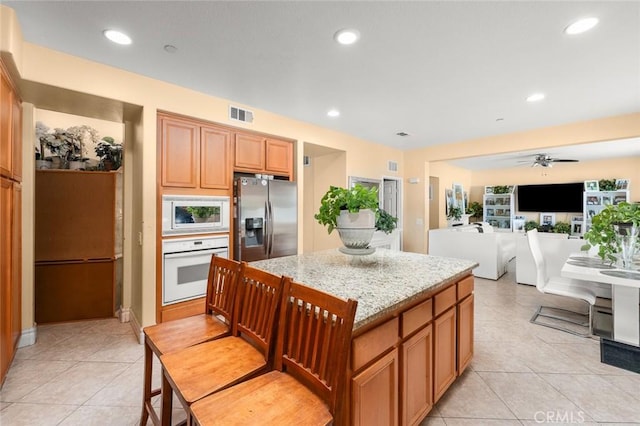 kitchen featuring light stone counters, stainless steel appliances, a center island, and light tile patterned floors