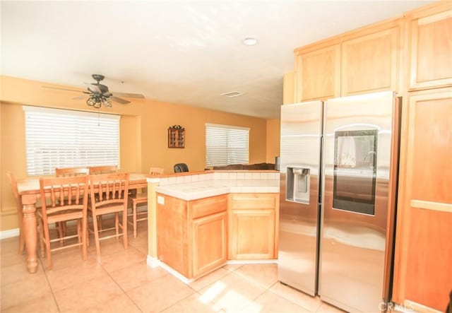 kitchen featuring light tile patterned floors, tile countertops, stainless steel fridge with ice dispenser, and light brown cabinets