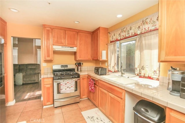 kitchen with sink, tile counters, light tile patterned floors, and stainless steel gas stove