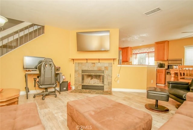 living room with a tiled fireplace and light hardwood / wood-style flooring