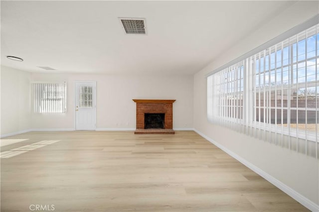 unfurnished living room featuring a fireplace and light hardwood / wood-style floors