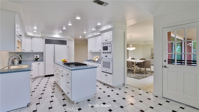 kitchen featuring white appliances, tasteful backsplash, visible vents, dark countertops, and a sink