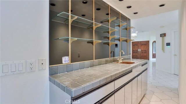 bar with tile counters, sink, and light tile patterned floors