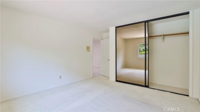 unfurnished bedroom featuring light colored carpet and a closet