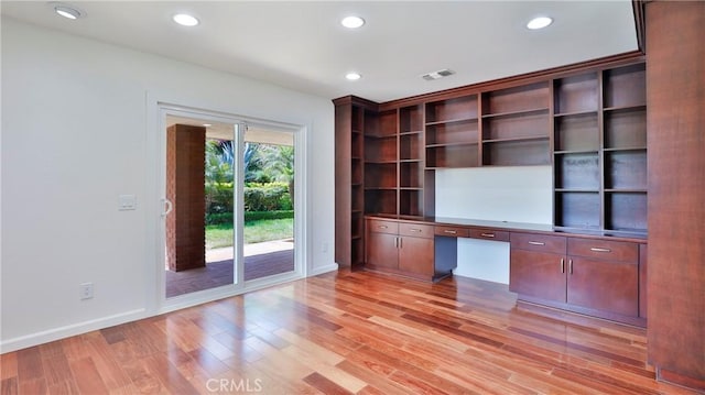 unfurnished office with light wood-type flooring, visible vents, built in desk, and recessed lighting