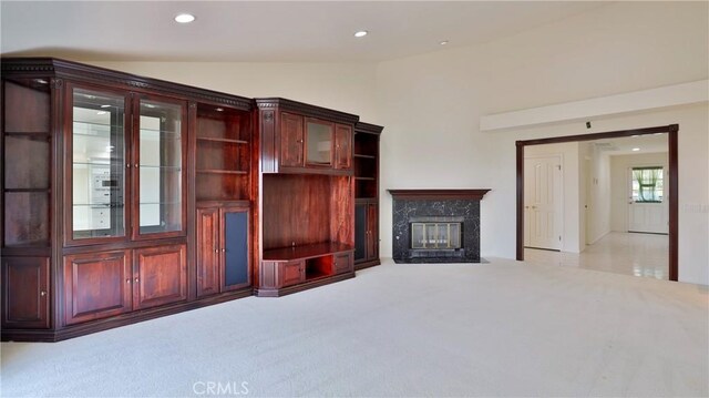 unfurnished living room featuring lofted ceiling, a fireplace, and light carpet