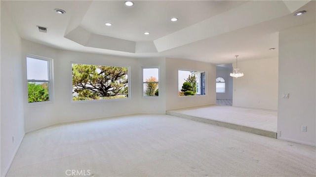 carpeted empty room with recessed lighting, visible vents, baseboards, a tray ceiling, and an inviting chandelier