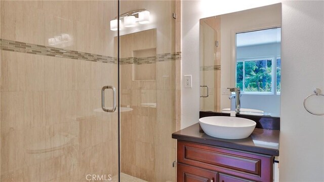 bathroom featuring a shower with door and vanity