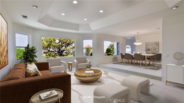 living room with light colored carpet, a tray ceiling, and a notable chandelier