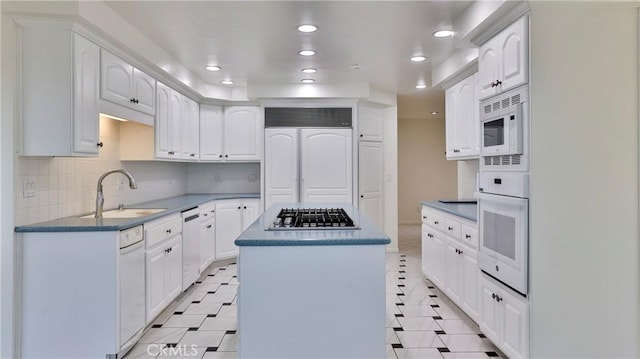 kitchen with tasteful backsplash, sink, white cabinets, a center island, and built in appliances