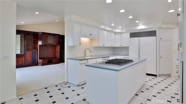 kitchen featuring sink, white cabinetry, a center island, tasteful backsplash, and stainless steel gas cooktop