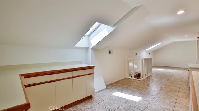 additional living space with lofted ceiling with skylight and light tile patterned floors