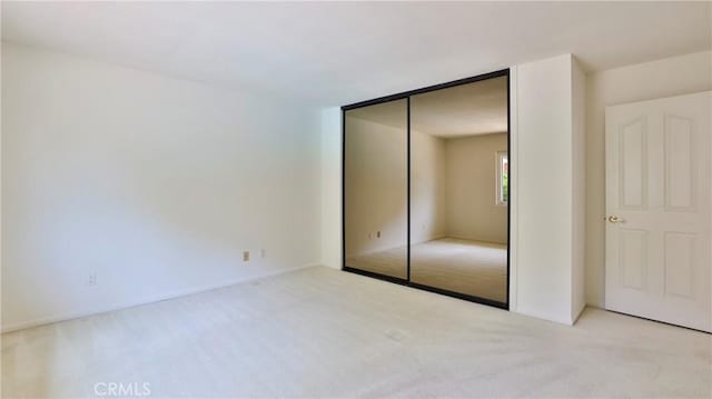 unfurnished bedroom featuring light colored carpet and a closet