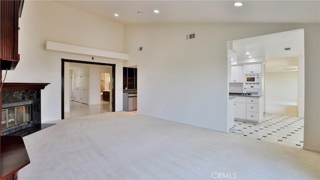 carpeted living room with high vaulted ceiling and a premium fireplace