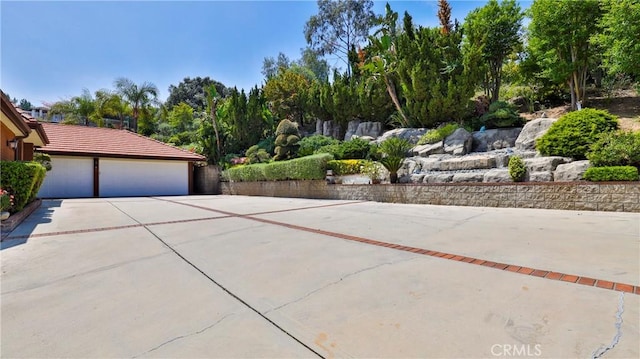 exterior space with an attached garage, concrete driveway, and a tiled roof