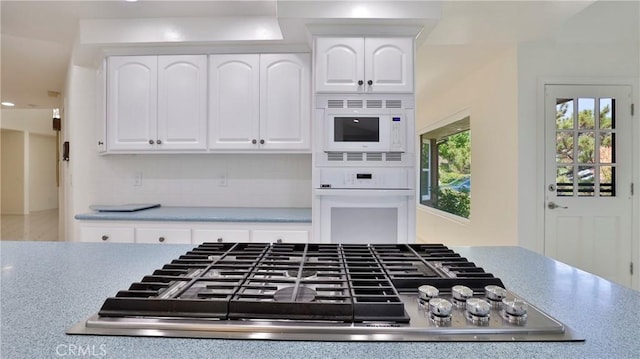 kitchen featuring white appliances, backsplash, and white cabinets