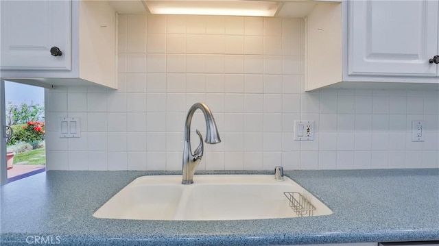 room details featuring white cabinetry, sink, and tasteful backsplash