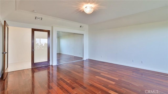 unfurnished bedroom featuring a closet, wood finished floors, visible vents, and baseboards