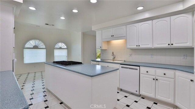 kitchen with a kitchen island, tasteful backsplash, white cabinetry, sink, and white dishwasher