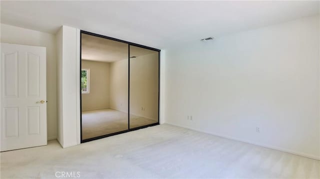 unfurnished bedroom featuring a closet and light carpet