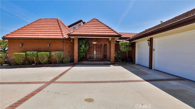 view of front of house with a garage, a tile roof, concrete driveway, and brick siding