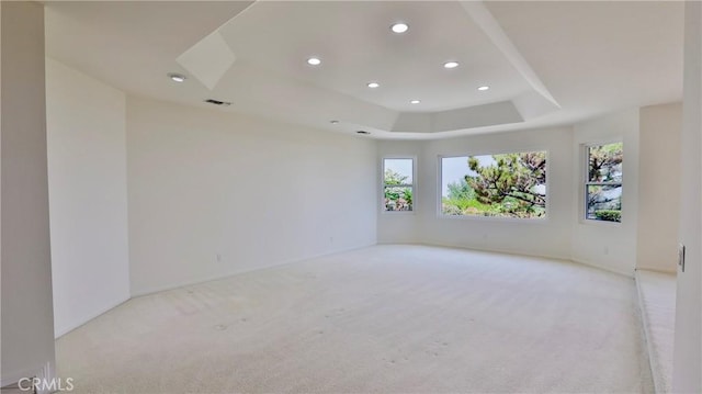 empty room featuring recessed lighting, visible vents, a tray ceiling, and light colored carpet