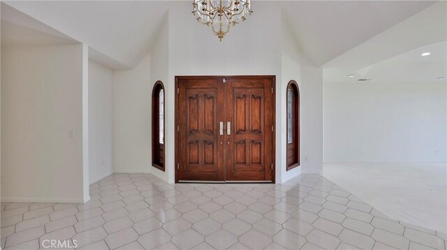 foyer entrance featuring a notable chandelier, a towering ceiling, and light tile patterned floors