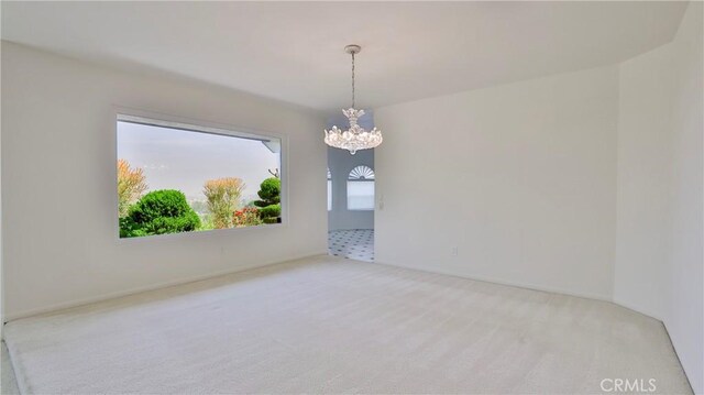 carpeted empty room featuring a chandelier