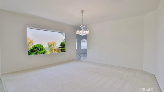 empty room featuring a chandelier and carpet flooring