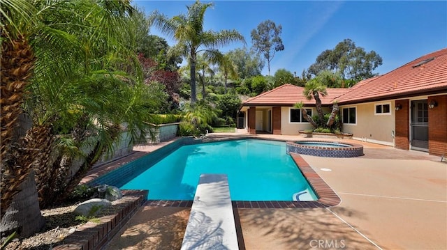 view of pool with a patio area, a pool with connected hot tub, and a diving board