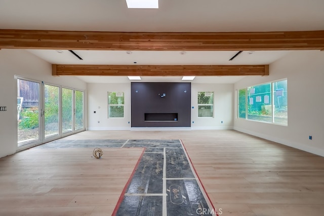 unfurnished living room featuring beam ceiling and light hardwood / wood-style flooring