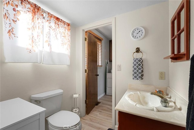 bathroom featuring vanity, washer / clothes dryer, hardwood / wood-style flooring, and toilet