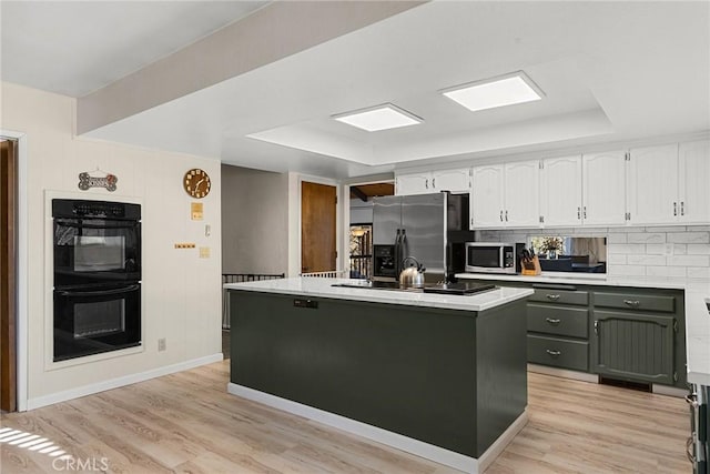 kitchen featuring a center island, light hardwood / wood-style floors, black appliances, white cabinets, and a raised ceiling