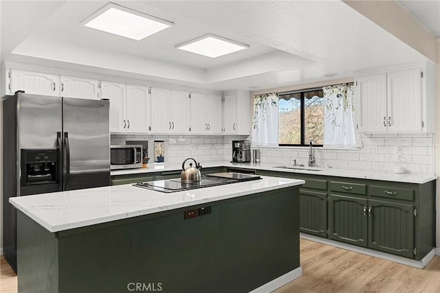 kitchen featuring appliances with stainless steel finishes, a tray ceiling, a kitchen island, and white cabinets