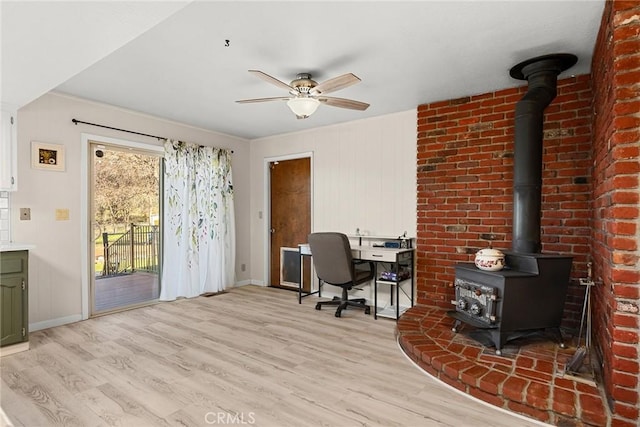 office area featuring ceiling fan, light wood-type flooring, and a wood stove