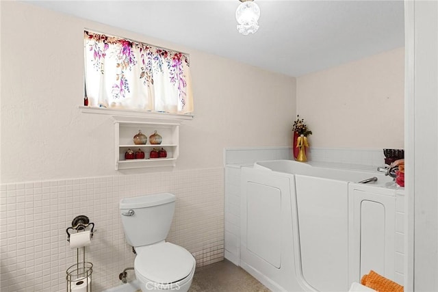 bathroom with toilet, tile walls, and a washtub