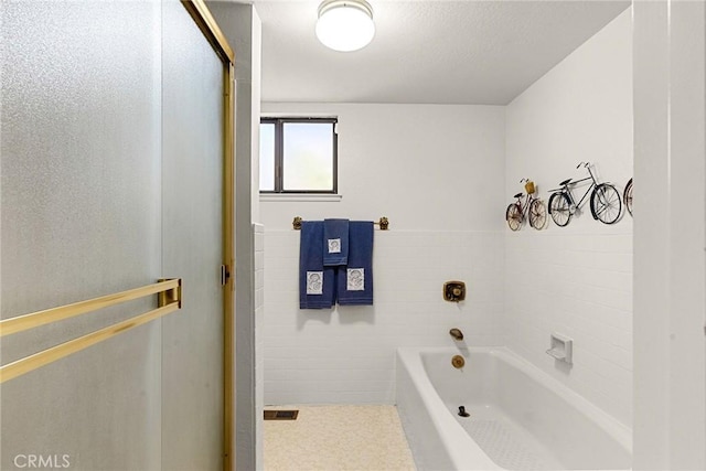 bathroom with tile walls and a bathtub